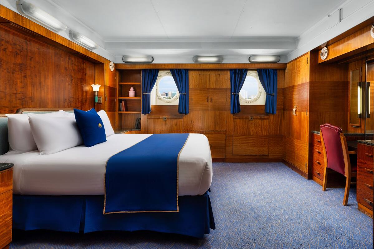 Un dormitorio con una cama grande, paredes de madera, un escritorio y una silla.