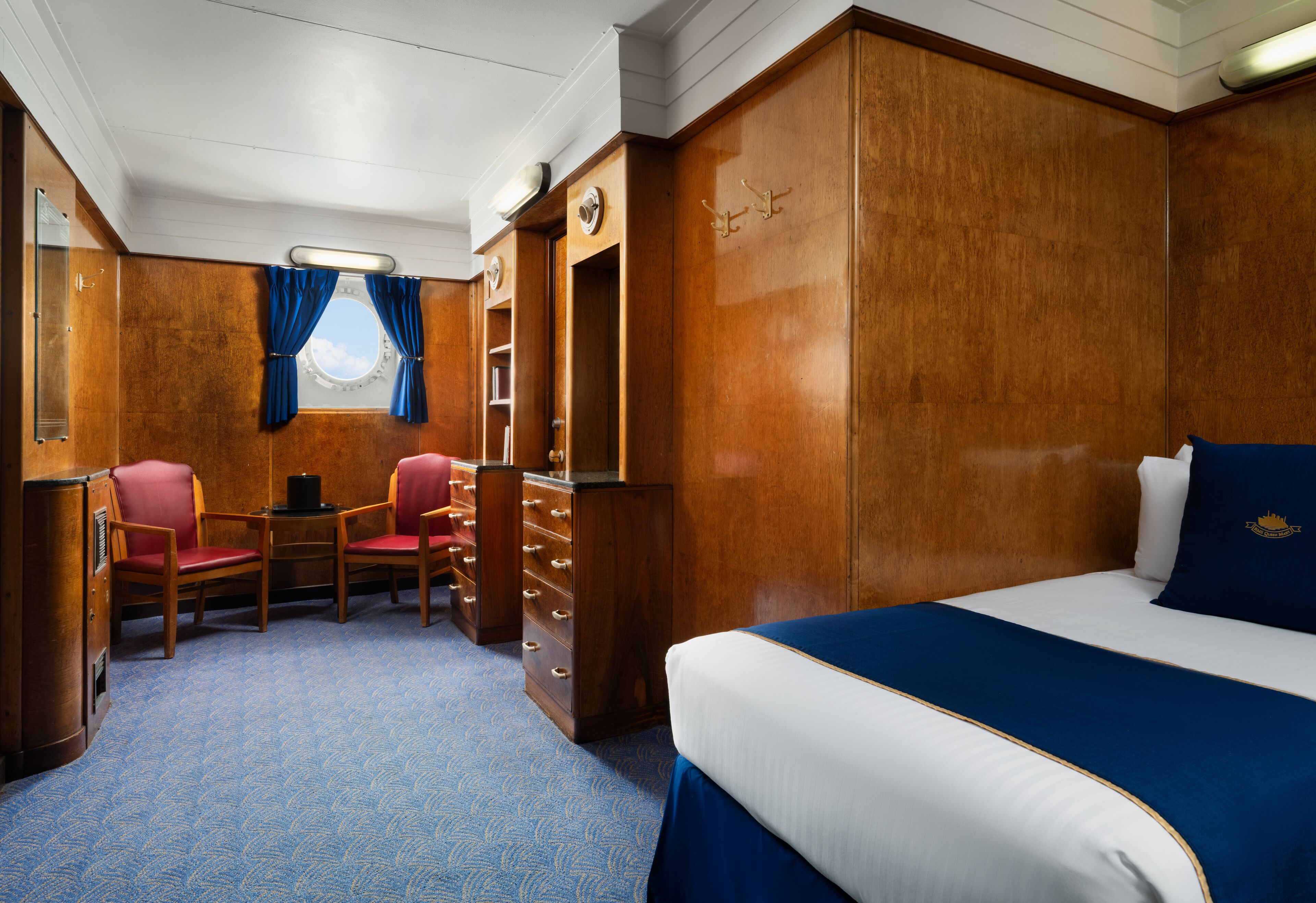 Habitación de hotel con una cama grande, un escritorio con dos sillas, una mesita y un armario.