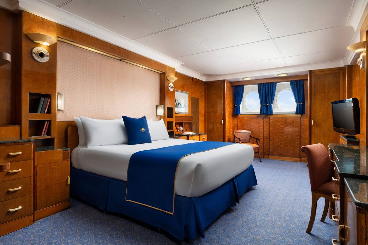 Un dormitorio espacioso con una cama grande, un escritorio y un televisor.