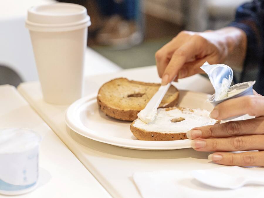 Una persona untando mantequilla en una rebanada de pan sobre un plato.