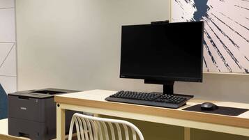 Un espacio de trabajo moderno con computadora, teclado, ratón e impresora sobre un escritorio.