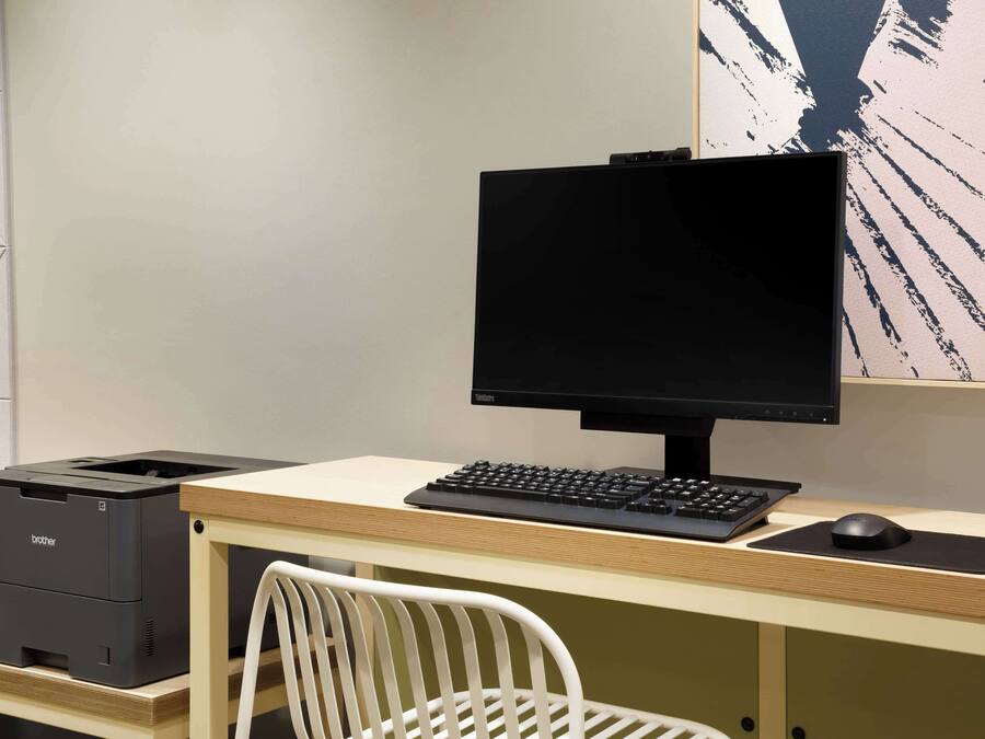 Un espacio de trabajo moderno con computadora, teclado, ratón e impresora sobre un escritorio.