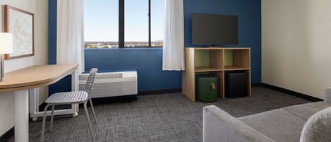 Habitación de hotel con escritorio, silla, televisión y vistas de la ciudad.