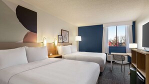 A hotel room with two beds, a desk, a chair, a TV, and a window with curtains. - Spark by Hilton Germantown Washington DC North (Germantown)