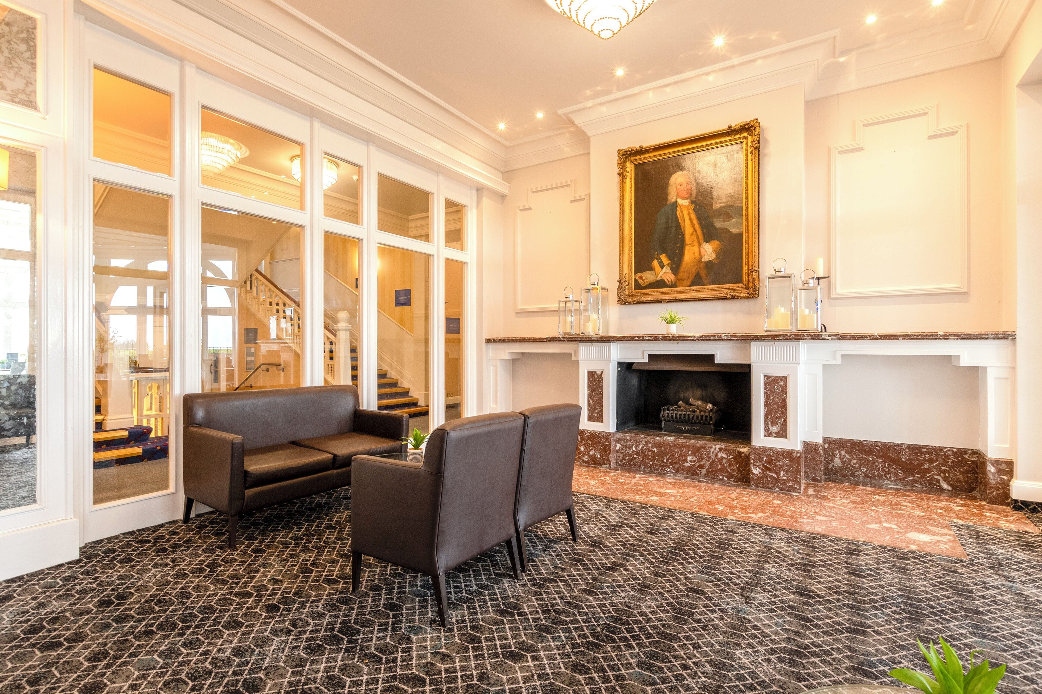 A room with a fireplace, a sofa, a chair, and a large painting on the wall.