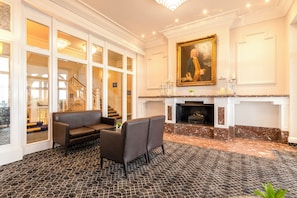A room with a fireplace, a sofa, a chair, and a large painting on the wall. - Bournemouth Carlton Hotel by Belvilla (Bournemouth)