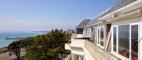 Un edificio residencial frente al mar con varios balcones, ventanas amplias y vista al océano.