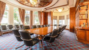 A conference room with a long table, black chairs, and a patterned carpet.