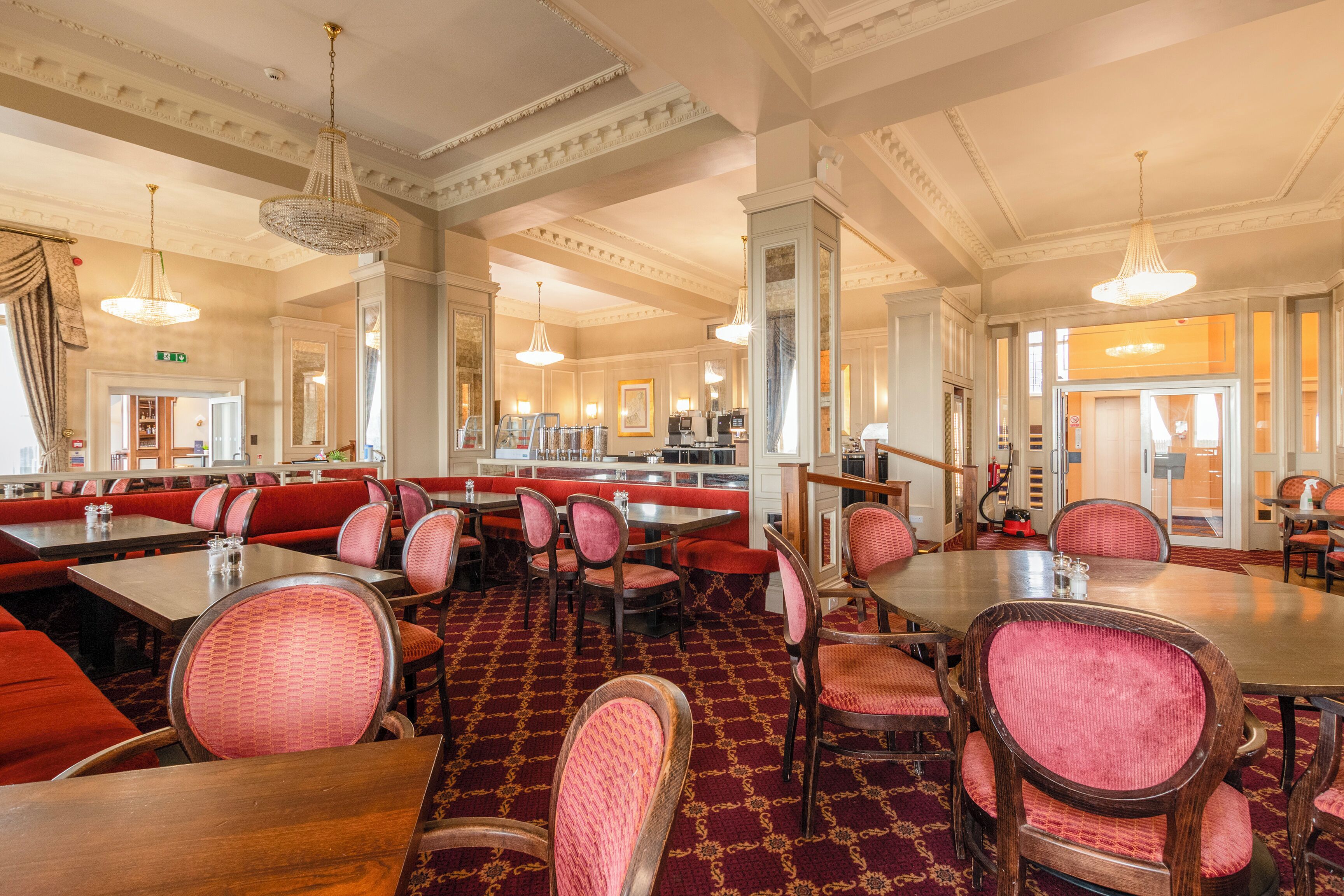 Un restaurante con cabinas, mesas redondas y sillas tapizadas en rojo.