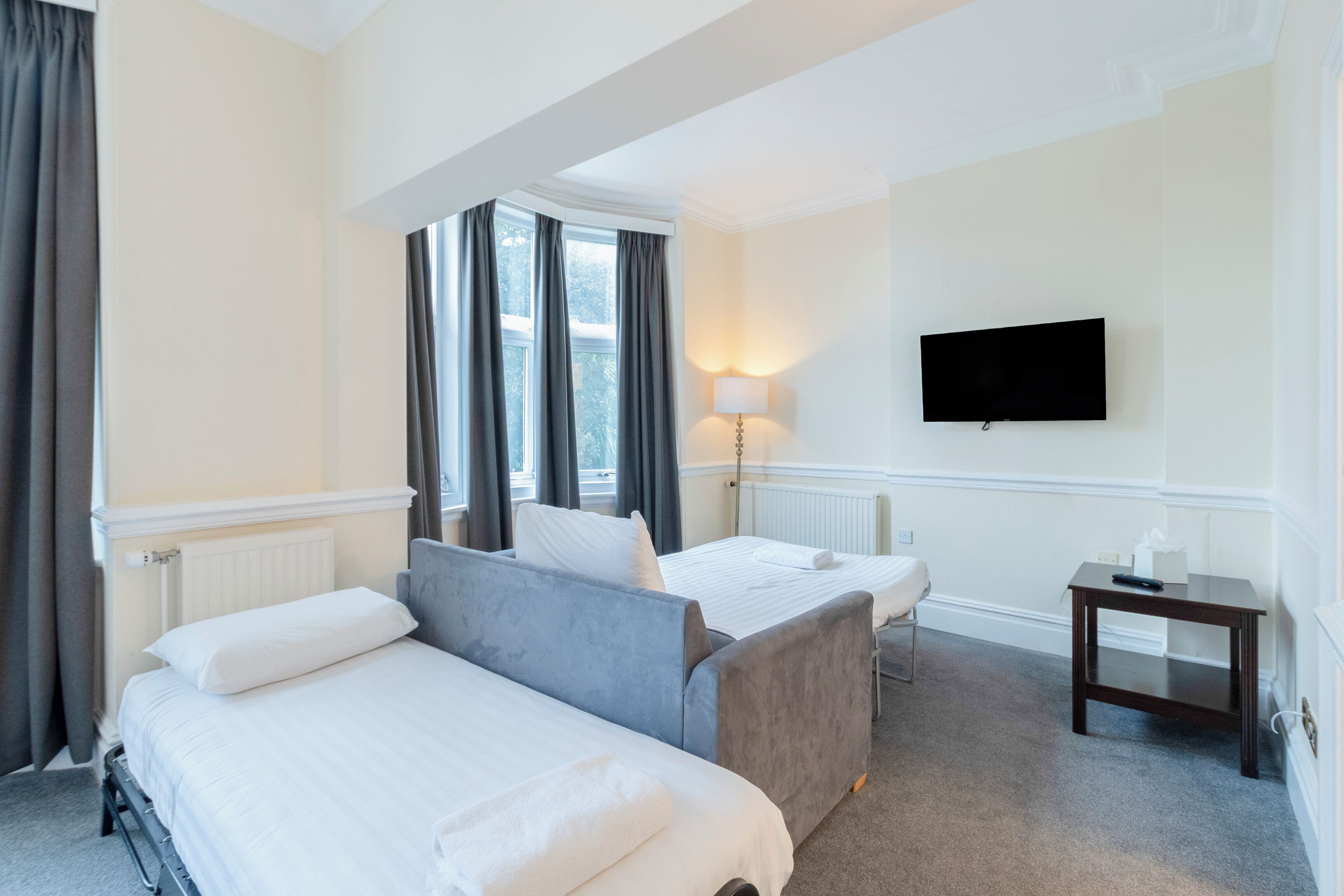 A hotel room with two beds, a TV, a lamp, and a small table.