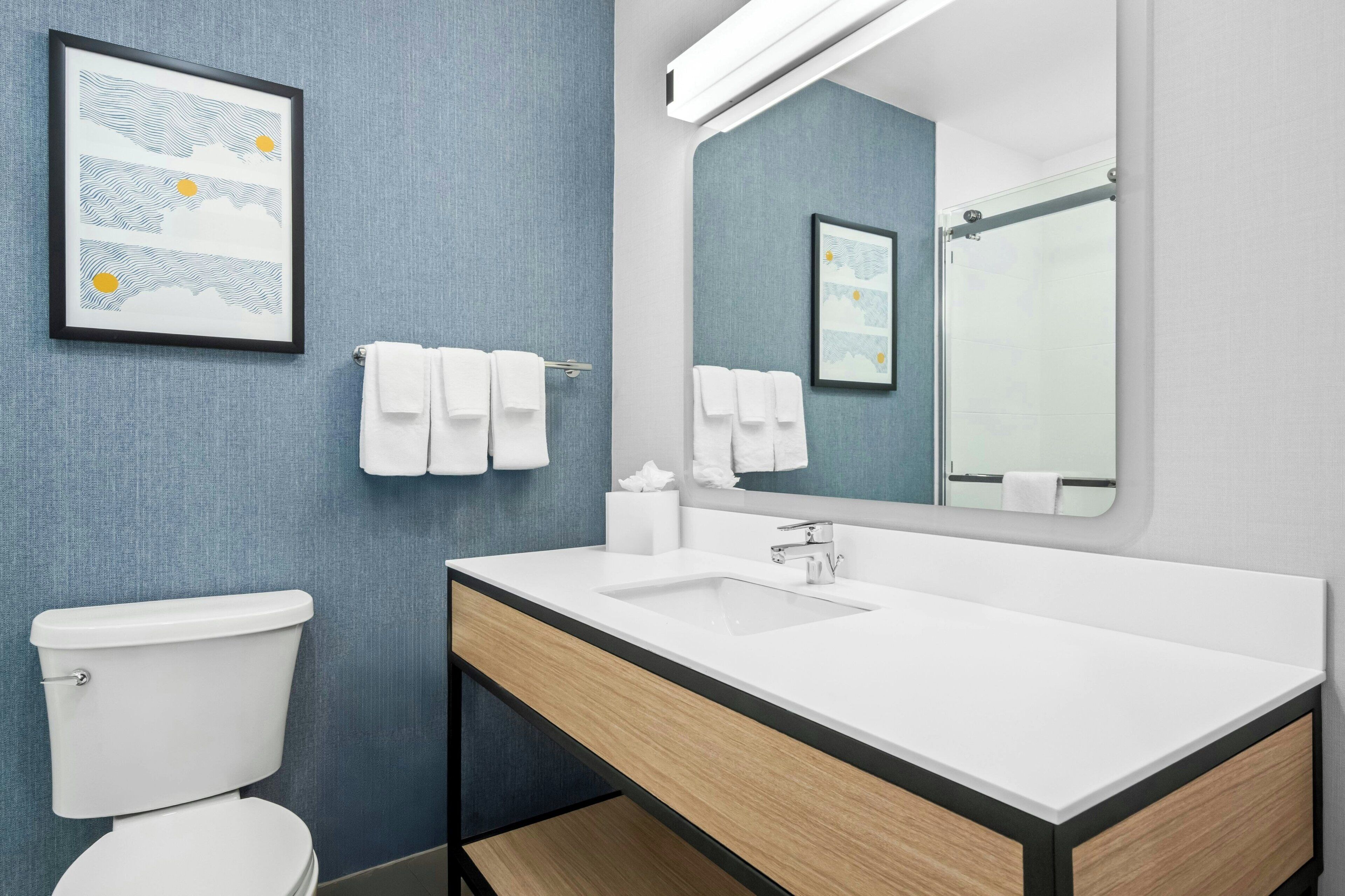Un baño moderno con inodoro, lavabo y espejo.