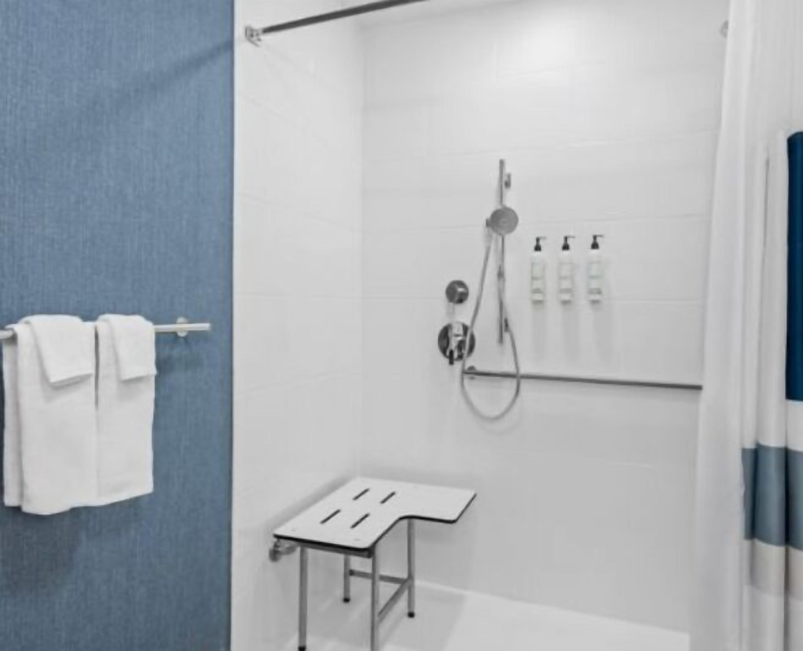Un bagno moderno con doccia, portasciuga-asciugamani e un piccolo tavolino.