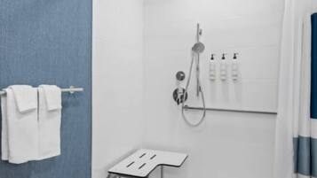 A modern bathroom with a shower, a towel rack, and a small table.