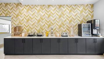 Una cucina moderna con parete a mosaico a spina di pesce, angolo caffè e frigorifero.