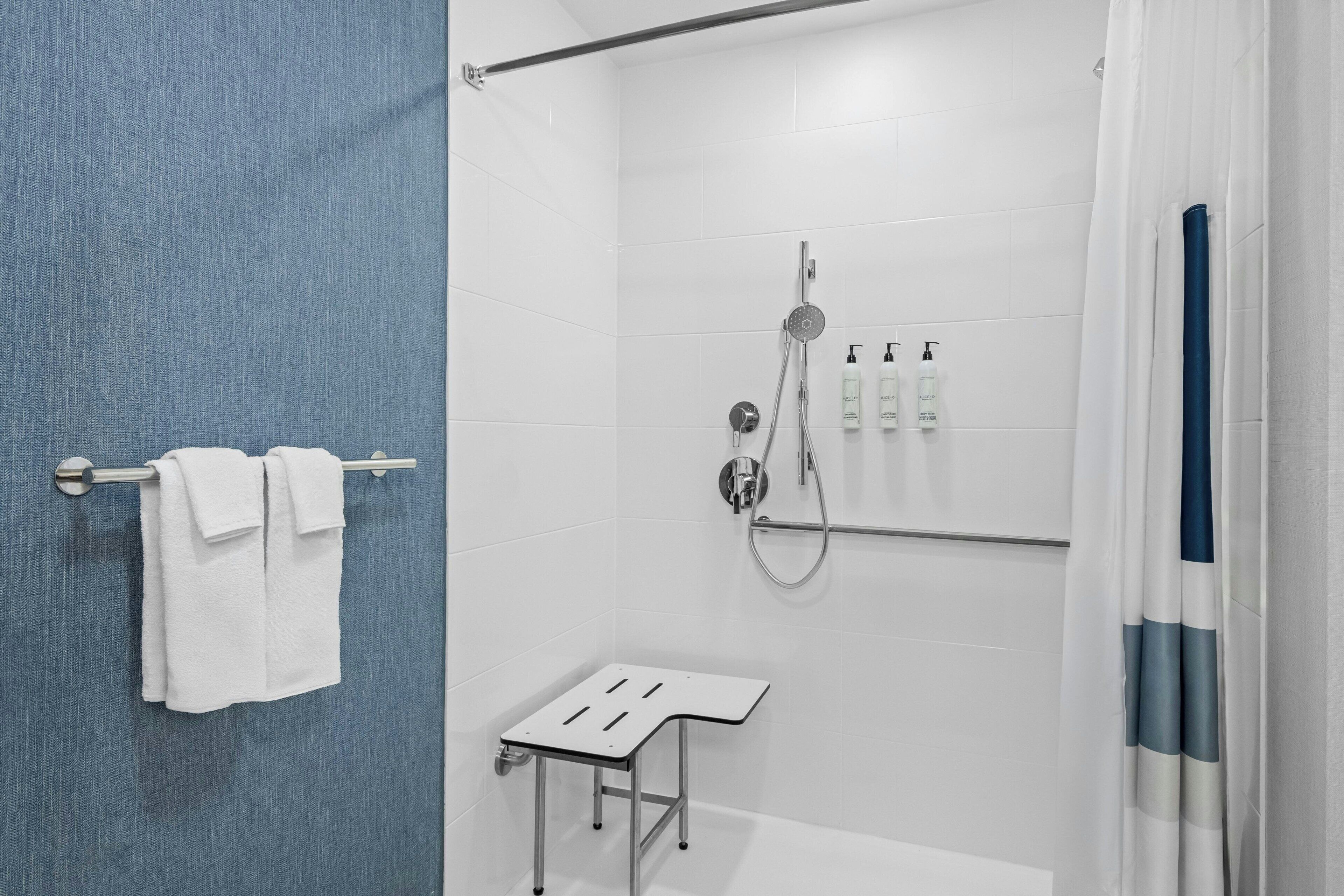 Un baño moderno con ducha, un perchero y una mesita.