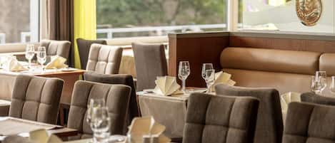 Un restaurante con mesas dispuestas para comer, con vistas a zonas verdes.