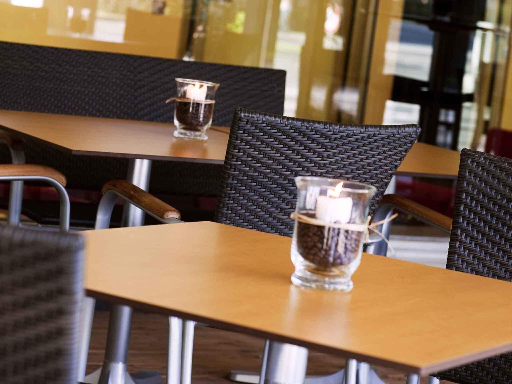 A restaurant interior with wooden tables and woven chairs.