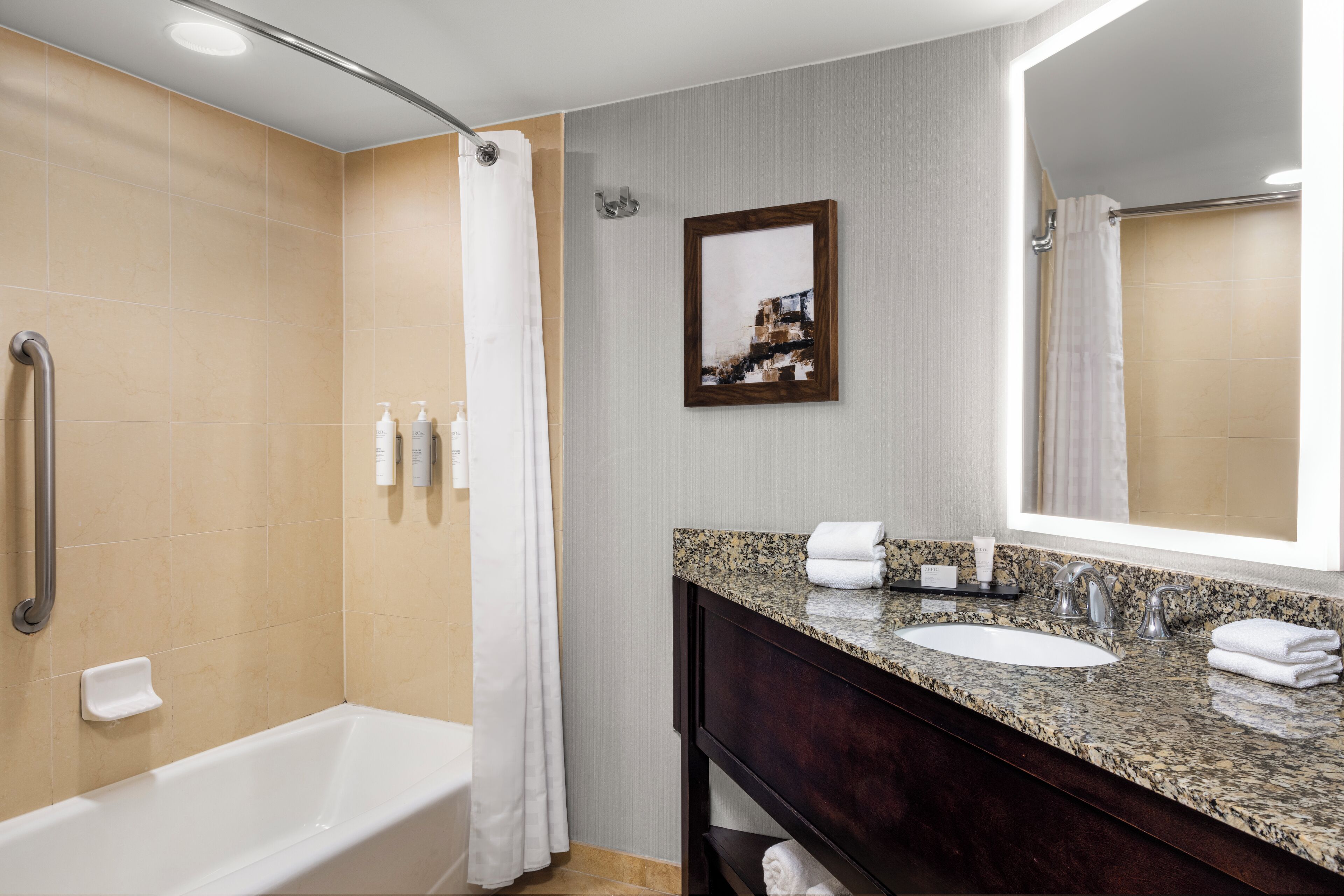 A modern bathroom with a bathtub, a sink, a vanity, and a shower area.