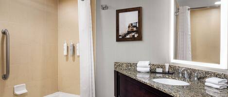 A modern bathroom with a bathtub, a sink, a vanity, and a shower area.