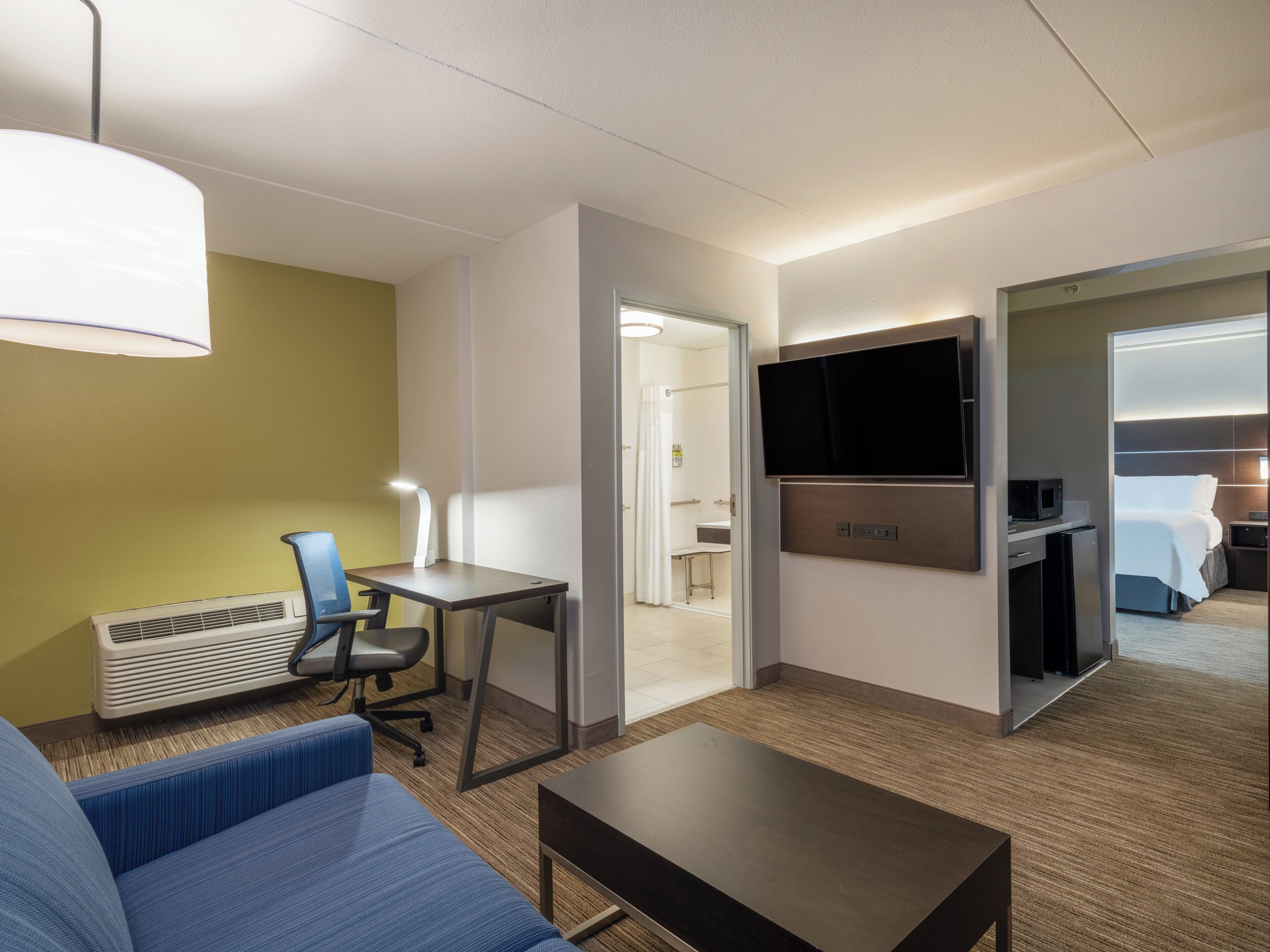 A hotel room with a sofa, a desk, a television, and a bed.