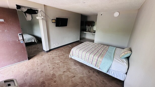 A small, compact room with a bed, a desk, and a mirror. - Hallmark Inn By OYO Fort Wayne (Fort Wayne)