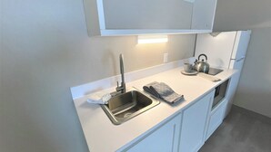 A compact kitchenette with a sink, kettle, and a small countertop. - FairBridge Extended Stay – a Kitchenette Hotel (Idaho Falls)