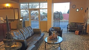 A lobby with a leather sofa, a glass coffee table, and a decorative metal sculpture. - FairBridge Extended Stay – a Kitchenette Hotel (Idaho Falls)