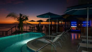 Una piscina al aire libre, sombrillas, sillones reclinables de piscina