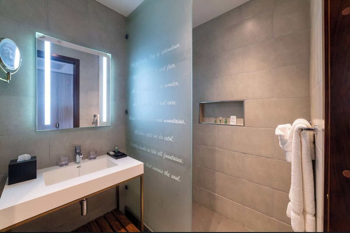 Ein modernes Badezimmer mit einem großen Spiegel, einem weißen Waschbecken und einer Duschkabine.