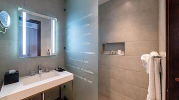 Un baño moderno con un espejo grande, un lavamanos blanco y una zona de ducha.