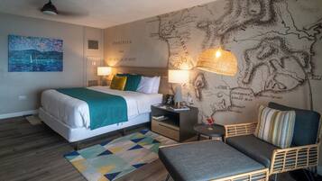 A hotel room with a bed, a sofa, a small table, a lamp, and a wall map.