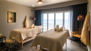 Une chambre d’hôtel avec deux lits, une chaise, un bureau et vue sur la mer.