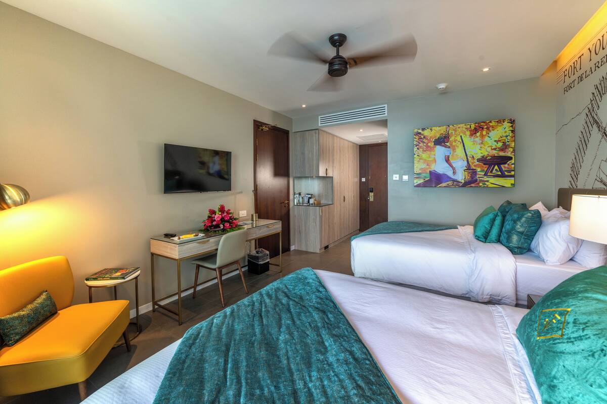 Ein Hotelzimmer mit zwei Betten, einem Schreibtisch, einem Stuhl und einem Fernseher.