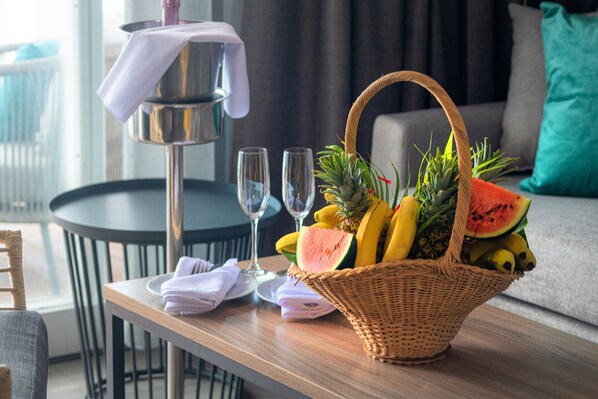 A wicker fruit basket on a table with a white tablecloth, two empty wine glasses, and folded napkins. - Fort Young Hotel (Roseau)
