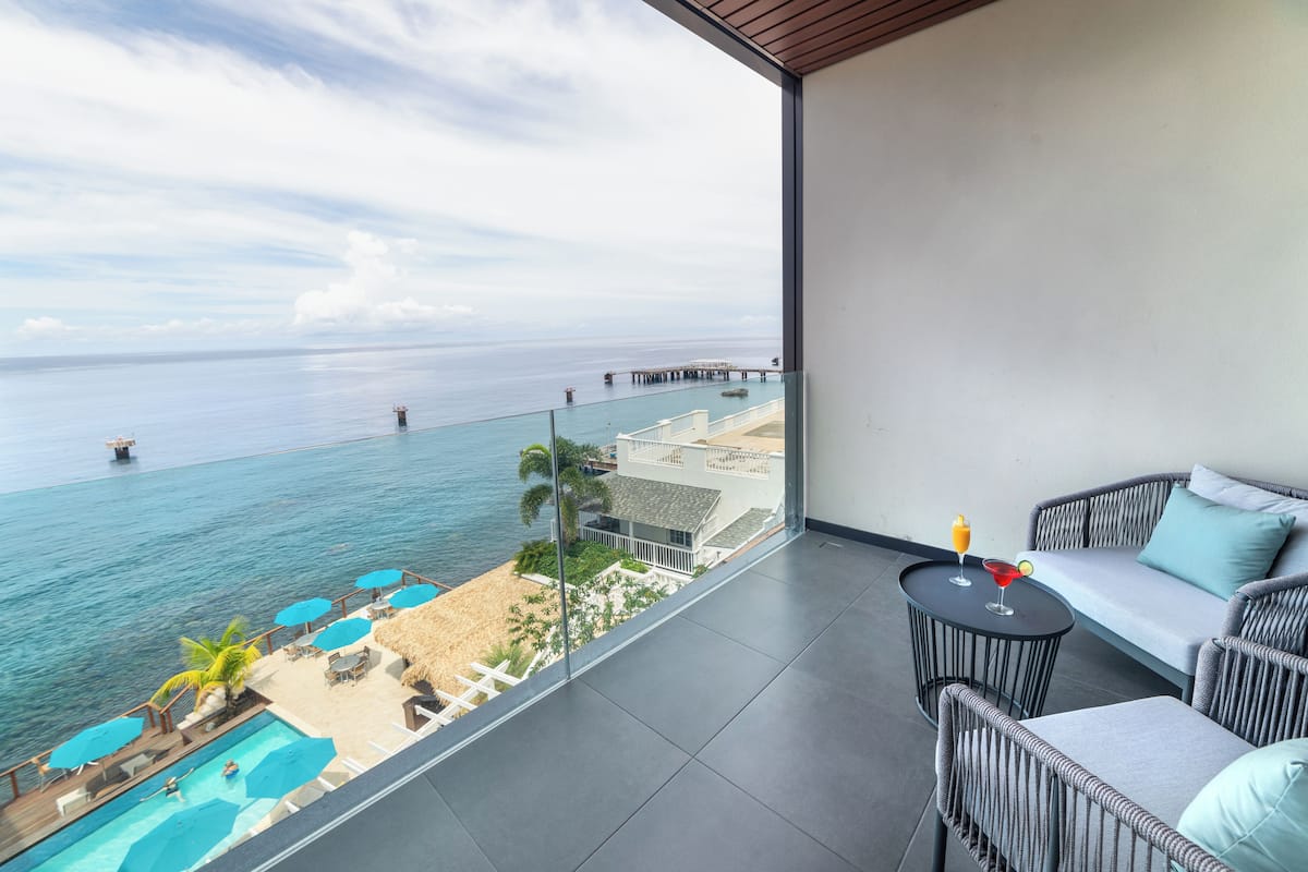 Ein Balkon mit Meerblick, einem Pool und einer Lounge mit Sofa und Tisch.