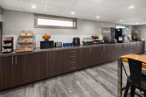 A modern kitchen with a long counter, equipped with a coffee machine, toaster, and food dispensers. - Days Inn by Wyndham Pierre (Pierre)