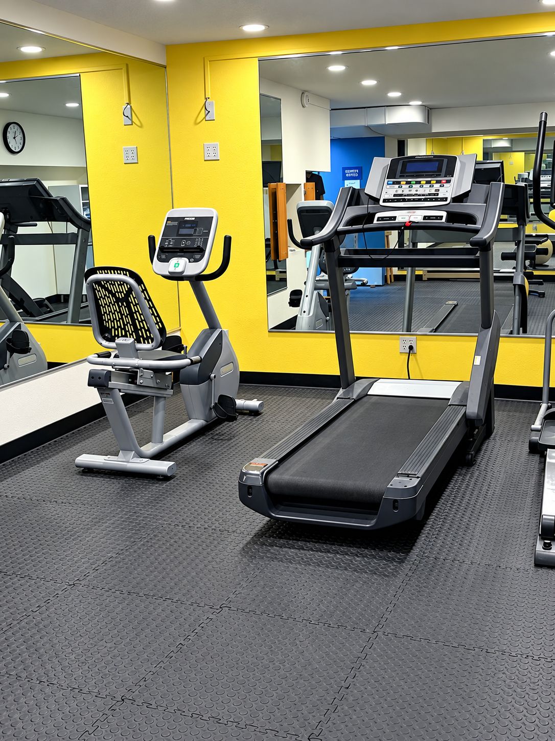 A gym with exercise equipment including a treadmill, stationary bike, and elliptical machine.