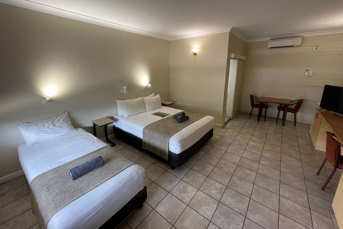 Habitación de hotel con dos camas, un escritorio y una silla.