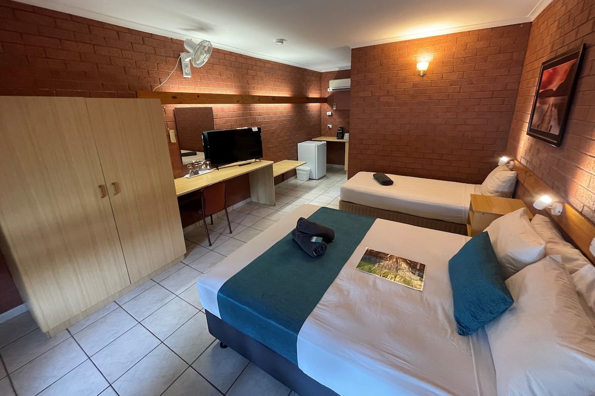 Habitación de hotel con cama, escritorio y armario.