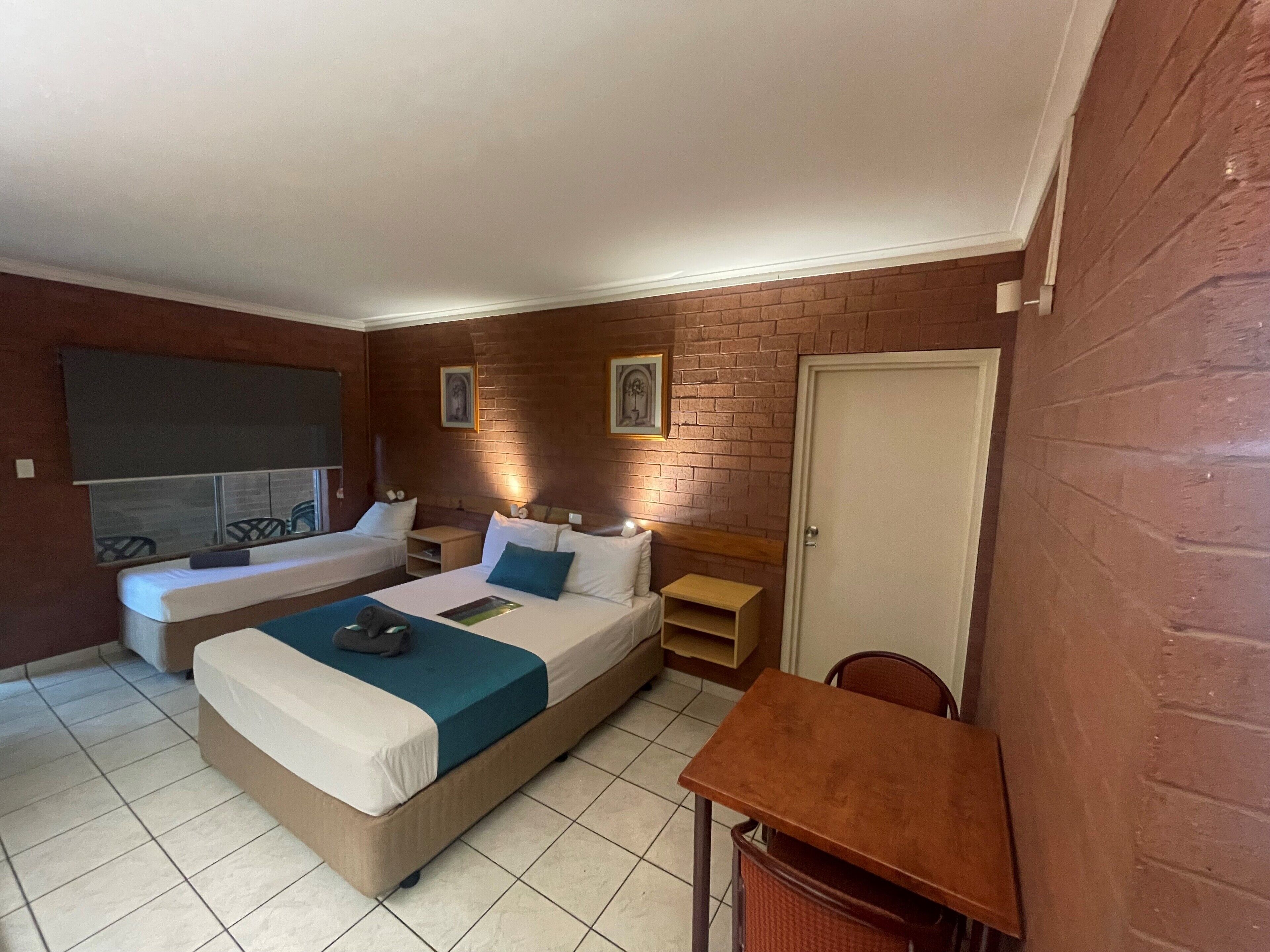 Una habitación con dos camas, una mesita y una silla.