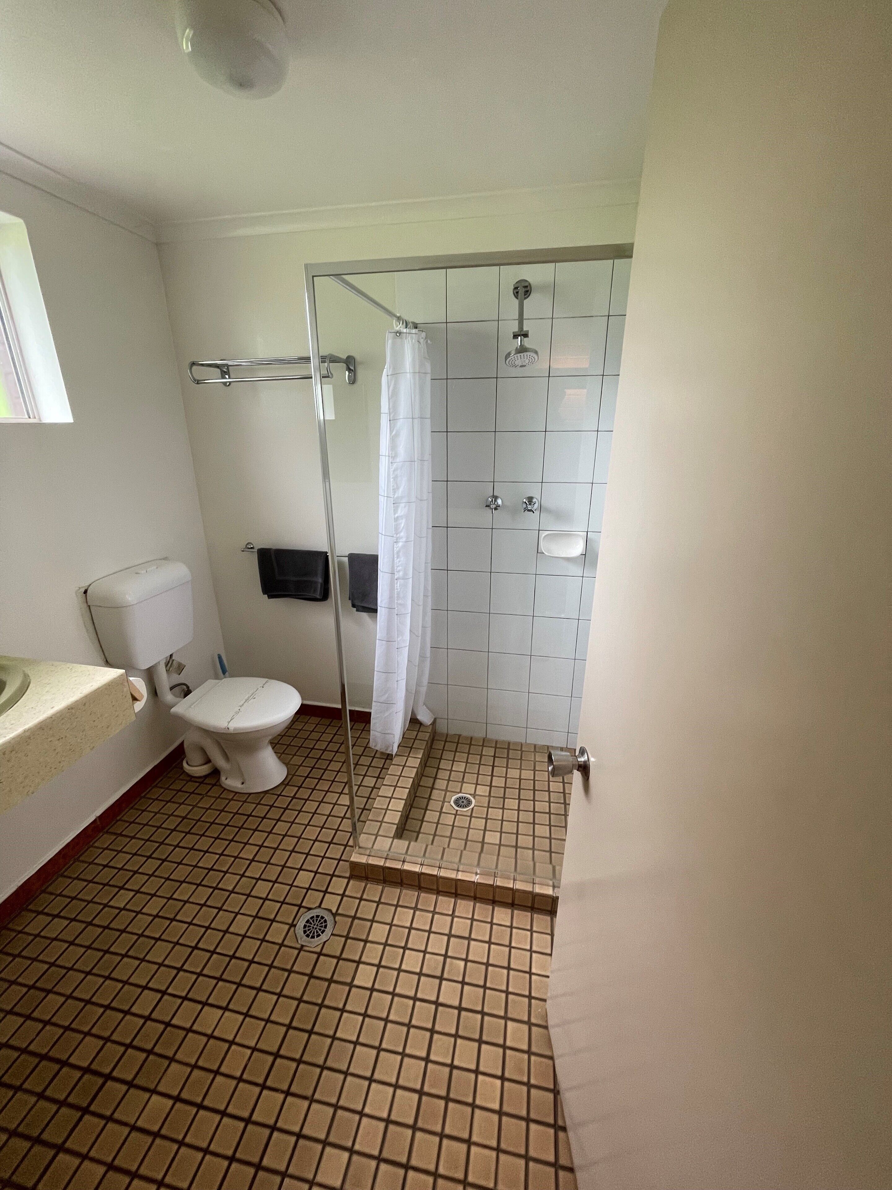 A bathroom with a toilet, sink, and shower area.