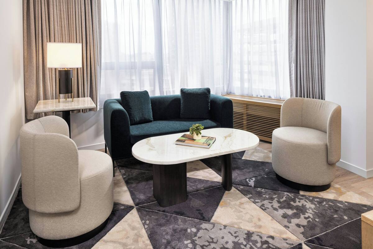 A modern living room with a sofa, two armchairs, a coffee table, and a lamp.