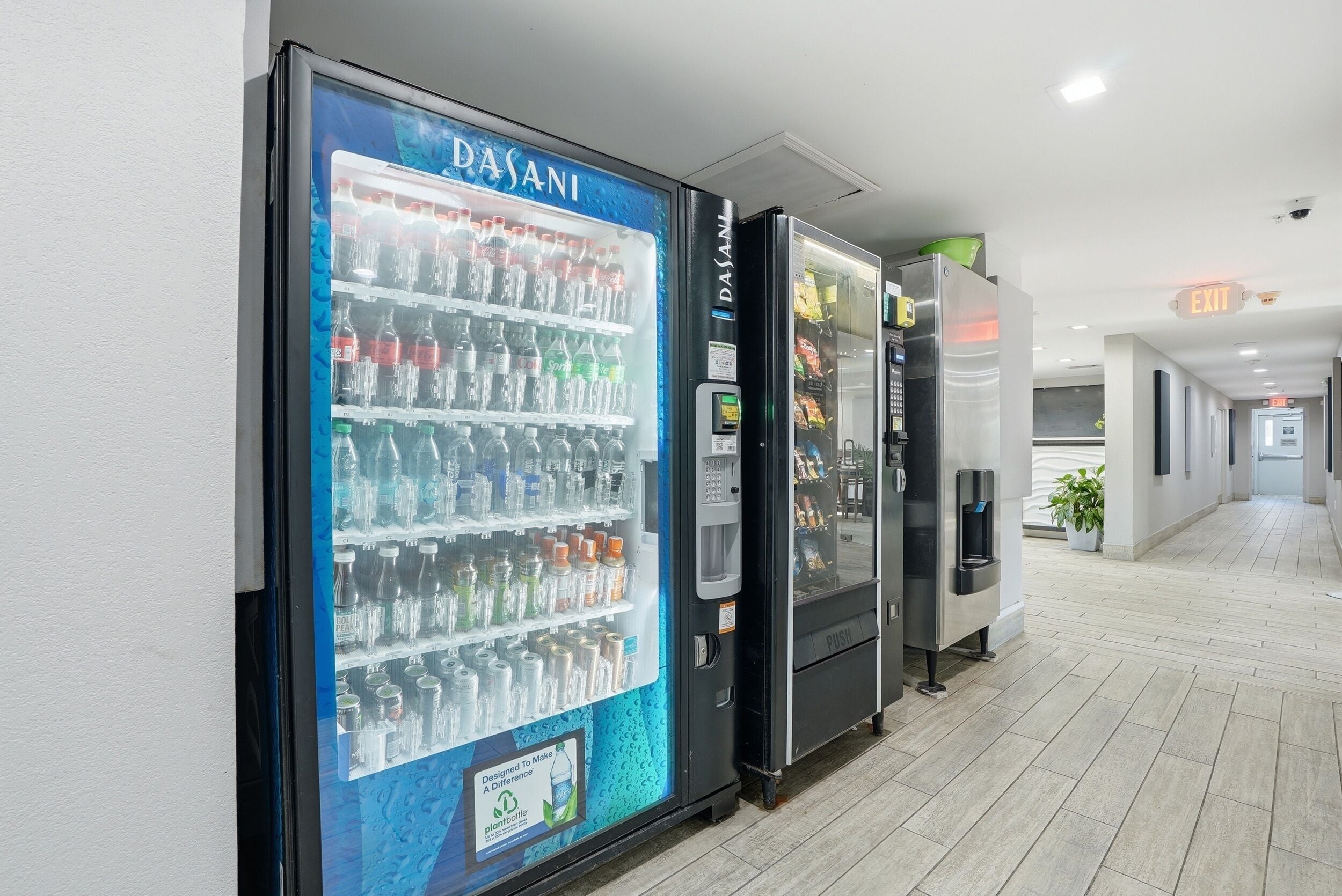 A corridor with vending machines labeled 'DASANI' and an 'EXIT' sign.