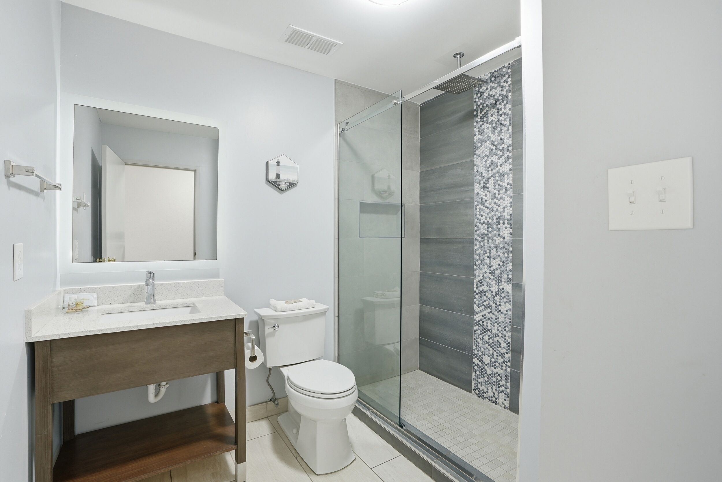 Un baño moderno con cabina de ducha de vidrio, inodoro y tocador con espejo.