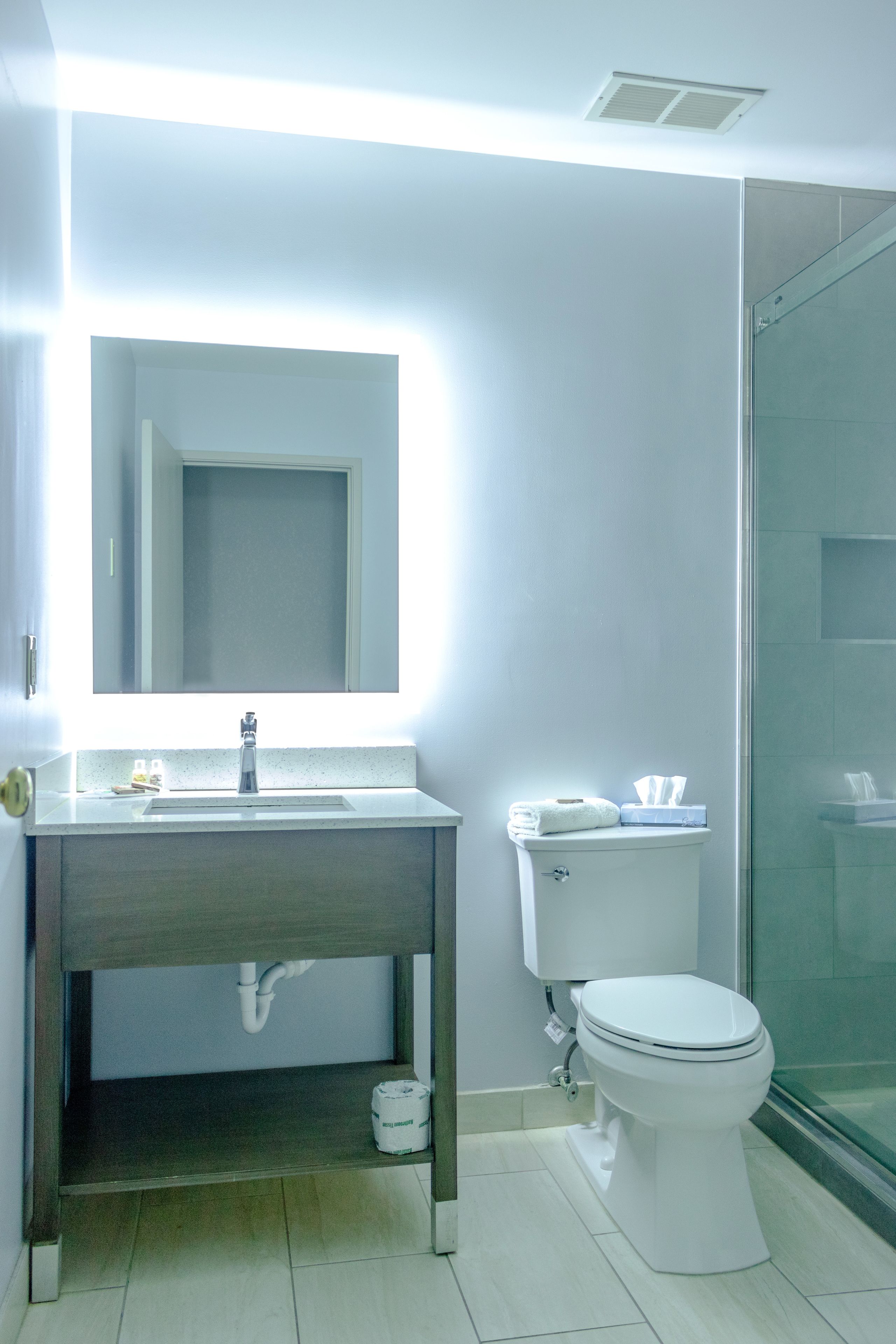 A bathroom with a white sink, mirror, and toilet.