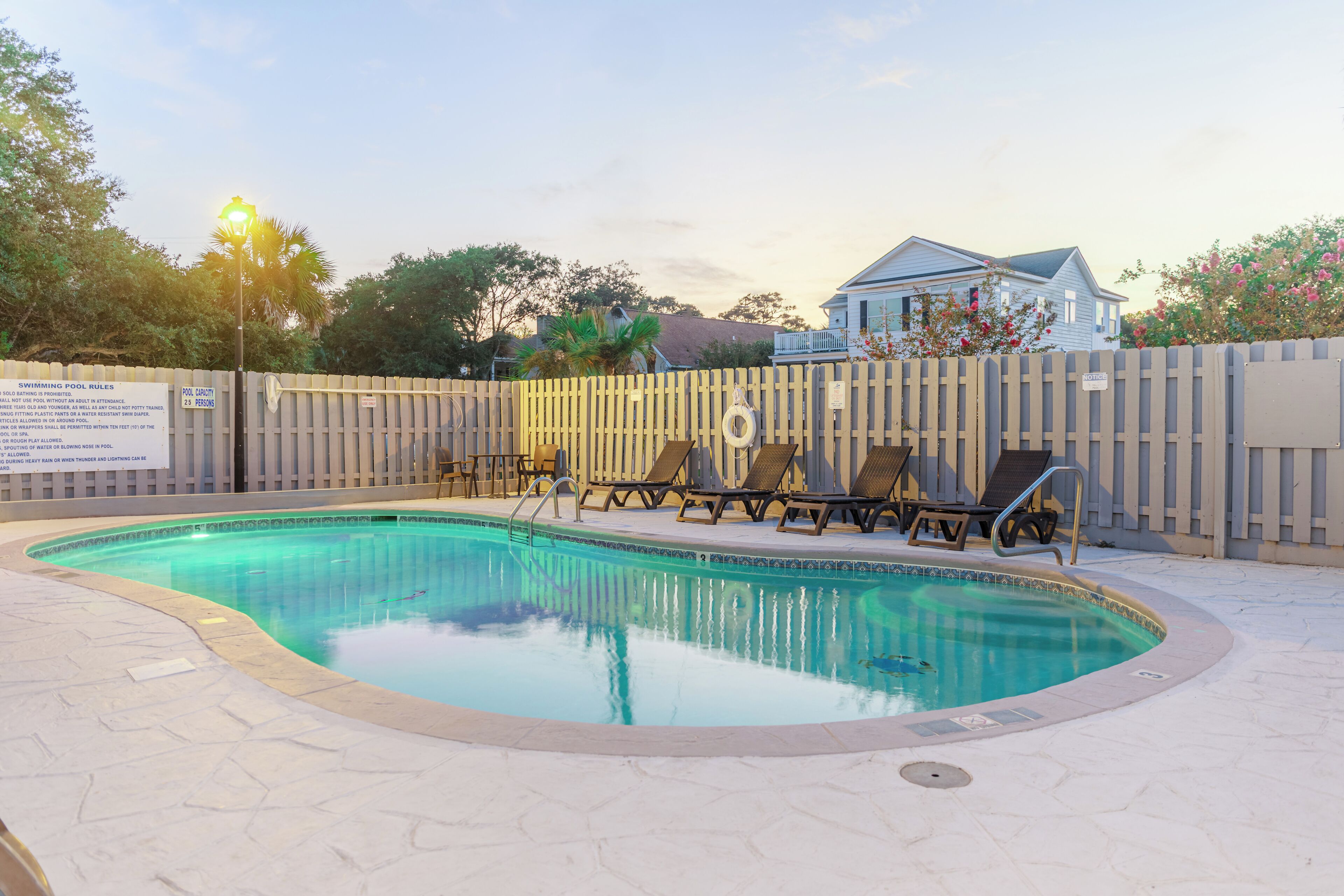 Une piscine avec des chaises longues et une clôture en bois.