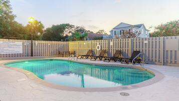 A swimming pool with lounge chairs and a wooden fence.