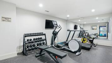 A fitness room with dumbbells, a bench, and cardio equipment.