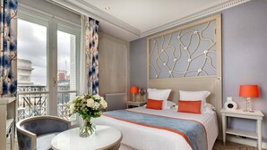 Una habitación de hotel con cama, una silla, una mesa y vistas a la ciudad.