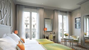 Habitación de hotel con dos camas, un escritorio, una silla y vistas a la ciudad.